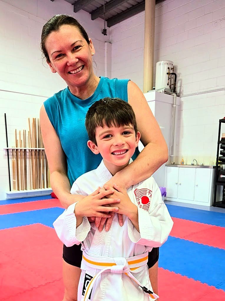 A mum hugging her young son in the dojo