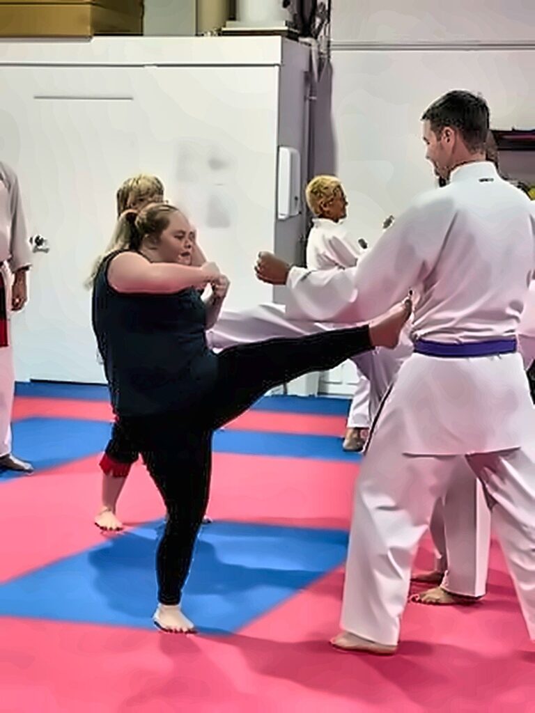 A participant practising a high kick with an instructor