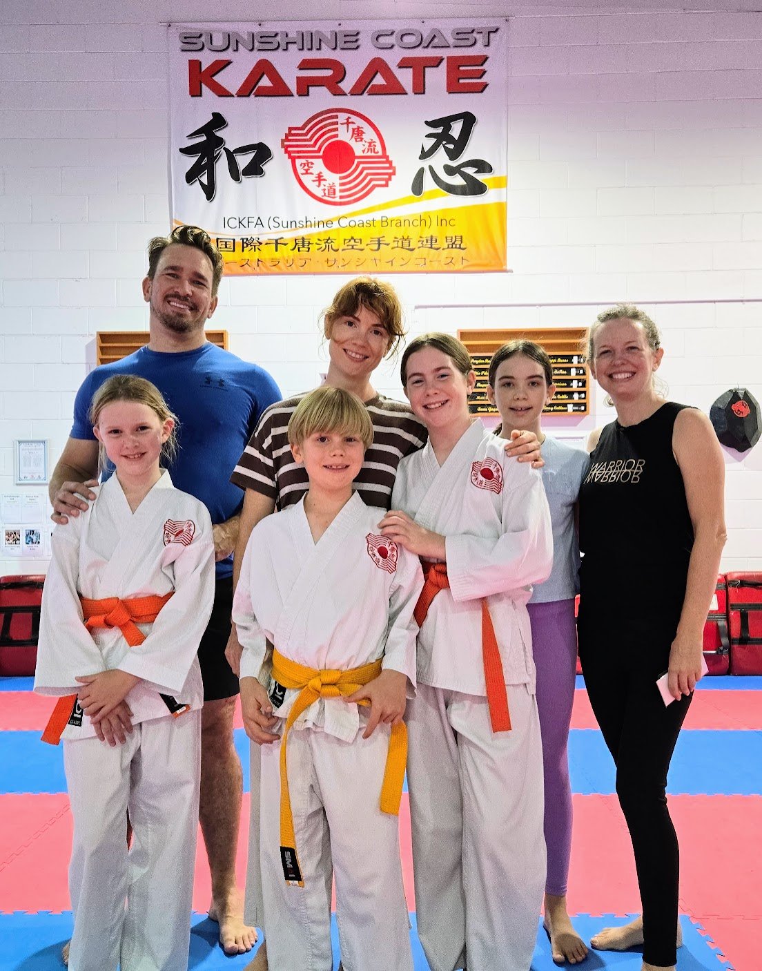 A family with their kids in karate uniforms, smiling in the dojo